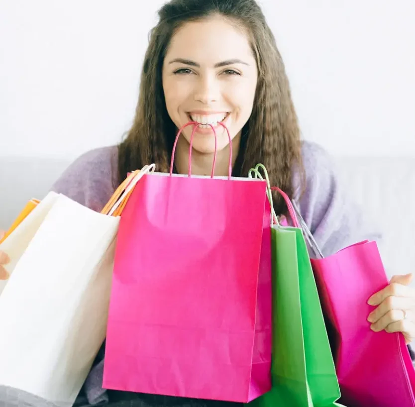 Happy woman sitting with vibrant shopping bags, enjoying a sale.